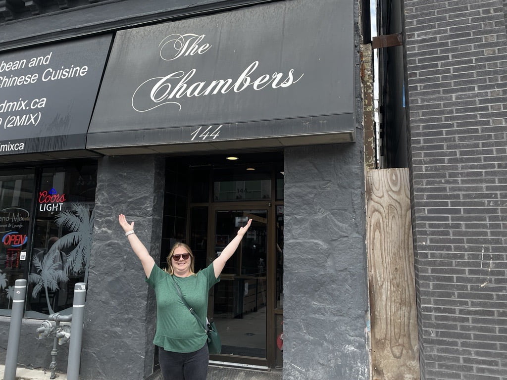 Joanna raises her arms in front of the Weber Chambers, 144 King Street W