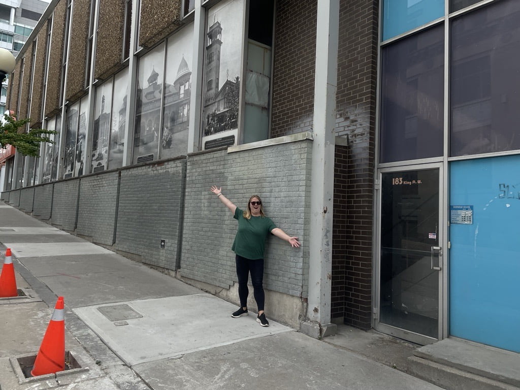 Joanna poses in front of a mural beside the entrance to 183 King Street W