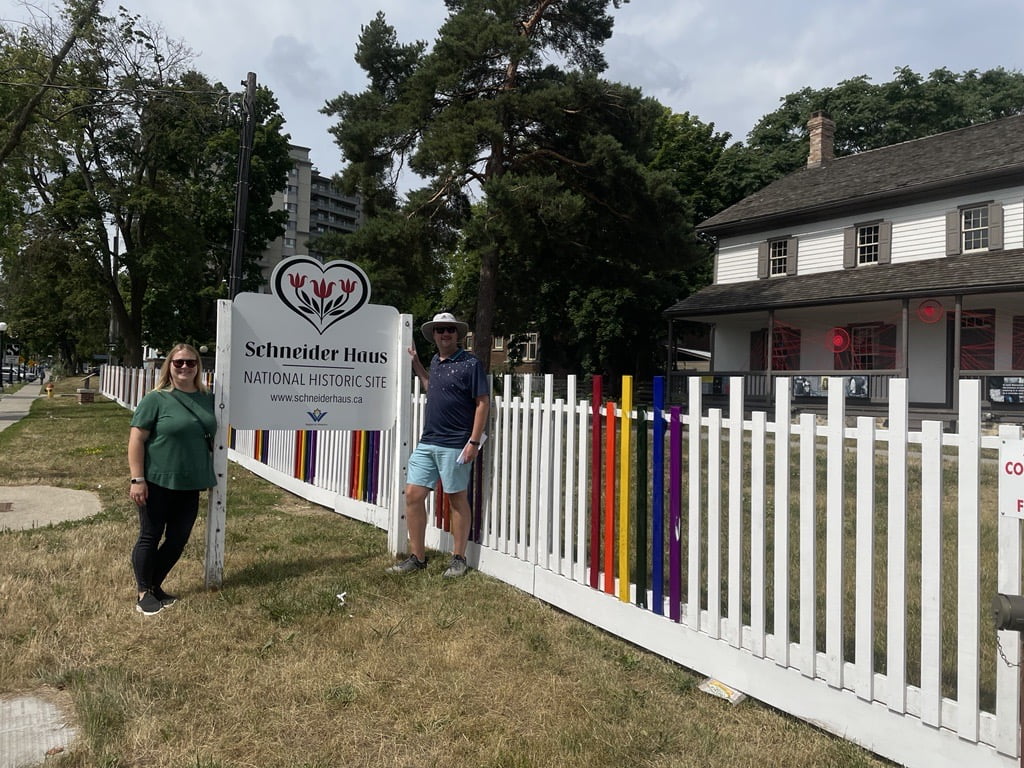 Joanna and Jared pose beside the Schneider Haus - National Historic Site sign